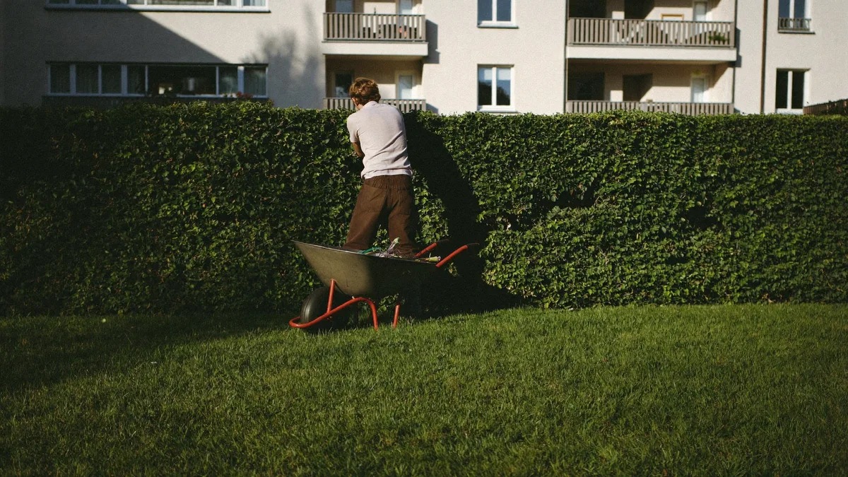 Heckenschnitt vor einem Mehrfamilienhaus (Symbolbild, KI-generiert)